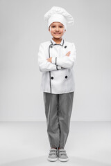 cooking, culinary and profession concept - happy smiling little girl in chef's toque and jacket over grey background