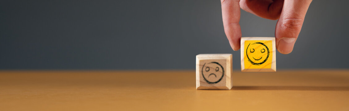 Hand holding smile face symbol on wooden cube