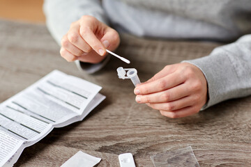 medicine, self testing and pandemic concept - hands of woman with swab and beaker making...