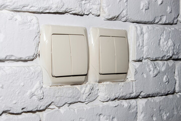 Electrical light switches on a gypsum brick wall.