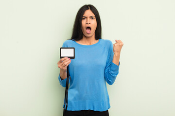 young pretty hispanic woman shouting aggressively with an angry expression. accreditation pass id...