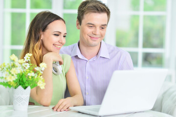 Portrait of young couple with laptop at home