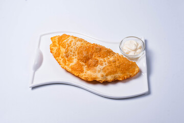 cheburek is a culinary product in the form of a semicircle of unleavened dough with a filling of chopped fatty lamb, onions, spices. on a white background