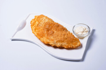 cheburek is a culinary product in the form of a semicircle of unleavened dough with a filling of chopped fatty lamb, onions, spices. on a white background
