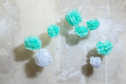 PonPons aus Papier in Mint und wei&szlig; vor einer Wand mit abgekrazter Tapete