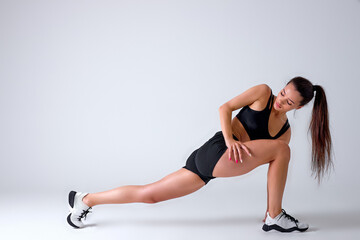 Fototapeta na wymiar Fitness woman doing lunges exercises for leg muscle workout training, active athlete lady is doing front forward one leg step lunge exercise, on white studio background, side view