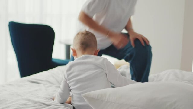 Cheerful mother and son jumping on the bed at home