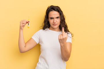 young pretty hispanic woman feeling angry, annoyed, rebellious and aggressive. thermometer concept