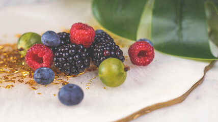 Summer fruity berry background. Table with berries and fruits. Summer breakfast, vacation, morning, sun. Berries, raspberries, blackberries, gooseberries. Vase with berries and fruits. 