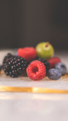 Summer fruity berry background. Table with berries and fruits. Summer breakfast, vacation, morning, sun. Berries, raspberries, blackberries, gooseberries. Vase with berries and fruits. 