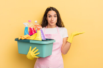 young pretty hispanic woman feeling puzzled and confused and doubting. housework an clean products...