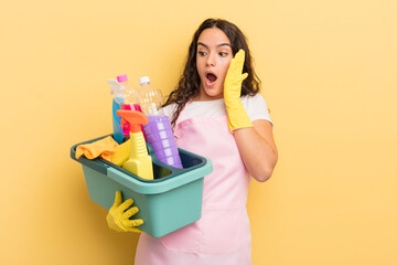 young pretty hispanic woman feeling happy, excited and surprised. housework an clean products...