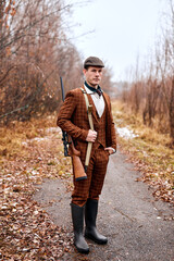 Young male hunter is going to hunt, dressed in brown stylish suit and hat. handsome good-looking...