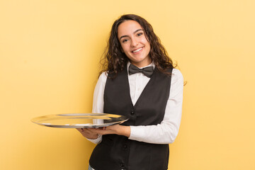 young pretty hispanic woman smiling cheerfully, feeling happy and showing a concept. waiter and...
