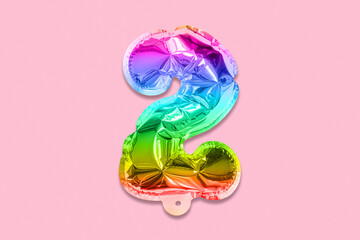 Rainbow foil balloon number, digit two on a pink background. Birthday greeting card with inscription 2. Top view. Numerical digit. Celebration event, template.