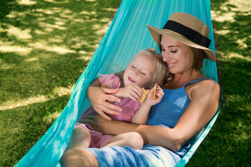 Fototapeta na wymiar loving family spends time together in summer time enjoy the little things. slow life. mom and little daughter relax in a hammock in the summer in the garden 