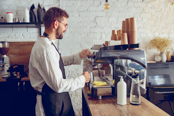Male barista using professional coffee machine in cafe