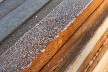 Wooden boards are covered with frost. Lumber. Wood for processing. Boards on the street