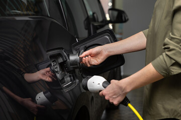 Fototapeta premium Close Up Of Woman's hands removing the lid of an electric car at home.