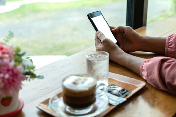 Hand holding a smartphone in a coffee shop textarea.