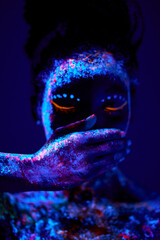 calm black woman with creative fluorescent prints paintings on skin, on body, close mouth. cosmic art on body. neon lights, ultra-violet rays, luminescence, silence, beauty concept