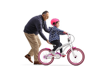 Grandfather teaching a little girl to ride a bicycle