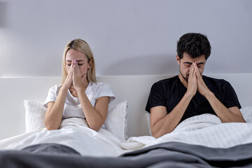 Unhappy young caucasian female and bearded male not talking after quarrel, on bed at home, frustrated blonde wife and husband ignoring each other, keep calm, relationship problem, family crisis