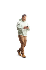 Naklejka premium Full length shot of a casual man walking and typing on a smartphone