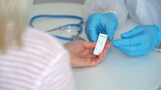 Doctor gives rapid antigen test for covid-19 to female patient in clinic. Results of research on coronavirus test. Quick swab method to SARS-CoV-2. PCR