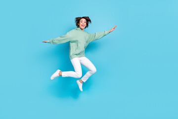 Full length photo of hooray young brunette lady jump wear hoodie pants shoes isolated on blue background