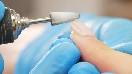 Manicurist in process of removing gel polish or acrylic from nails using  manicure machine. Process of hardware manicure in the salon.  Nail manicure process in a beauty salon. Nail beauty salon.