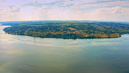 Aerial view over beautiful suburb with a wide river with privat houses. Top view over a people settlement near water...