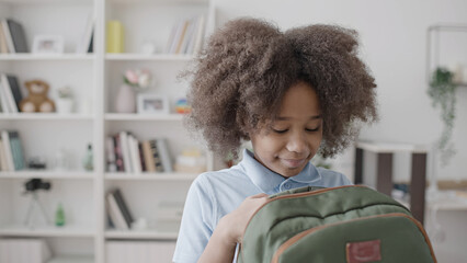 Little girl packing books into backpack, getting ready for school, education