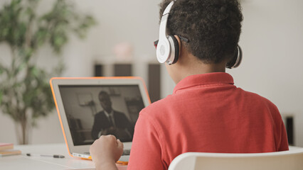 African american boy in headphones learning foreign language online with tutor