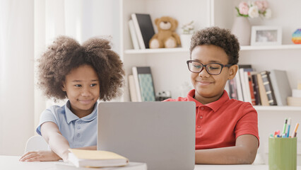 School kids working on laptops solving tasks, doing homework together
