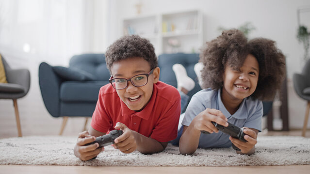 African american brother and sister playing video games, holding gaming joysticks in hands