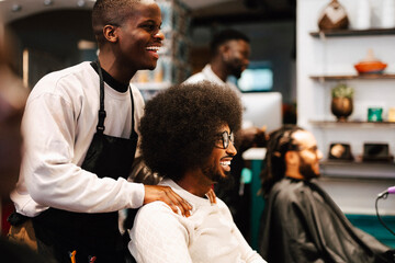 Happy male hairdresser talking with customer in barber shop
