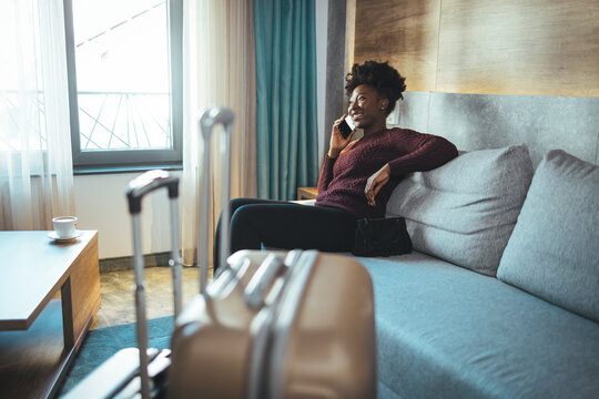Close-up of luggage and blurred background of a happy tourist woman in a hotel after check-in. The concept of travel and vacation. She reports that she arrived safely via her smartphone
