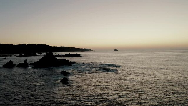 Aerial flight along rocky coastline of Punta Cometa Mazunte during sunset in Mexico