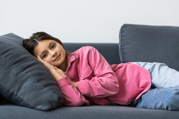 Fototapeta premium Beautiful school teen girl smile while lying on a sofa in the living room