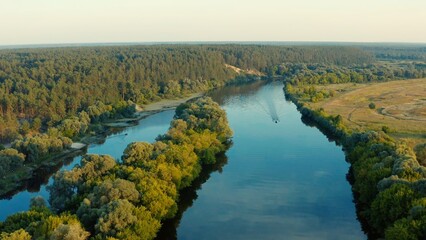 Aerial view above a beautiful landscape with a  river while sunset. Aerial view from drone flies over a beautiful summer landscape.