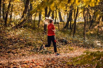 Rear view of young woman running in park.