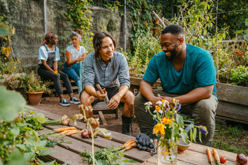 Happy male and female farmers talking while sitting in community garden