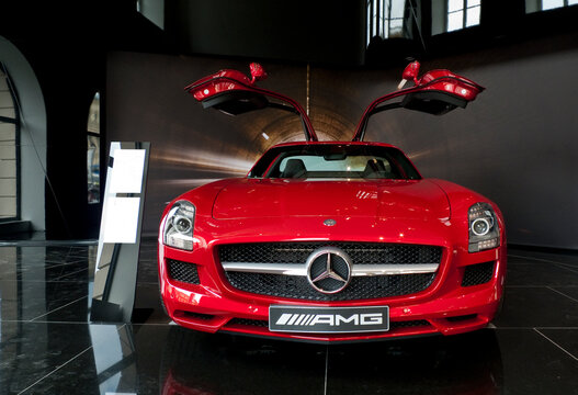 Frontal view of a red SLS Mercedes AMG with opened wing doors in showroom