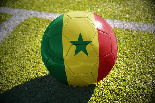 football ball with the national flag of senegal lies on the green field