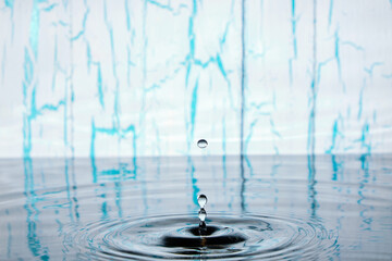 Splash and ripples on water from falling raindrop on light wooden background with peeling paint.