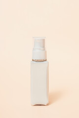 face lotion in a glass bottle with a dispenser on a beige background