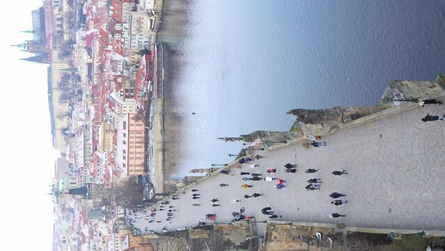 People are walking on Charles bridge, whose rooftops are covered by snow, Prague in the winter