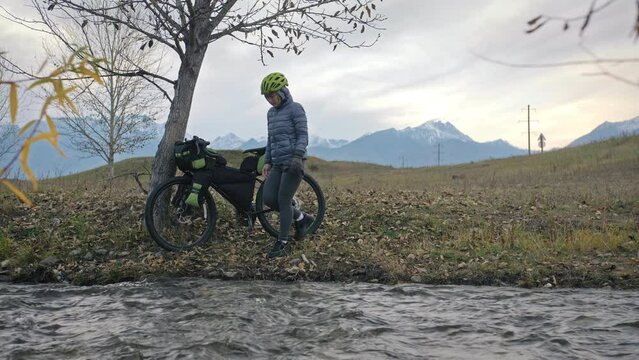 The woman travel on mixed terrain cycle touring with bikepacking. The traveler journey with bicycle bags. Sport tourism bikepacking.