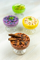 Smoothie or pudding with chocolate, hazelnuts and almonds served in a bowl for breakfast with several other smoothies in background